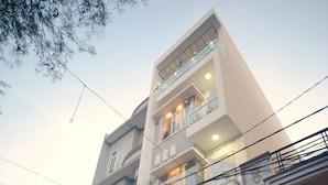 A modern building with a glass facade, a sign reading "Homestay," and a visible entrance with steps leading up to it. - Quy Nhon Homestay BnB (Quy Nhon Nam)