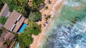 A beachfront property with a swimming pool, beach access, and palm trees. - Royal Indigo Villa (Unawatuna)