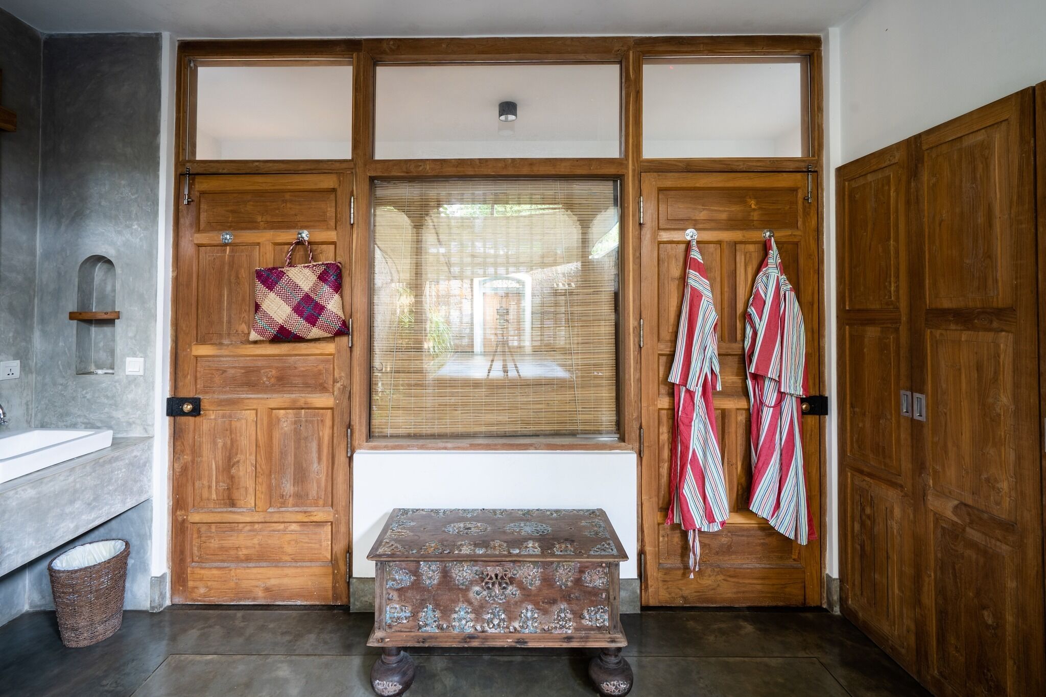 Una porta in legno con una finestra, una panchina e un cesto.