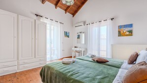 Een slaapkamer met twee bedden, een witte kledingkast, een bureau en een schilderij aan de muur.
