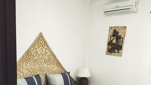 A neatly made bed with a striped bedspread and a decorative headboard. - Wirason 2-Bedroom Pool Villa (Koh Samui)