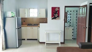 A compact kitchen with white cabinets, a refrigerator, a stove, and a window. - Wirason 2-Bedroom Pool Villa (Koh Samui)