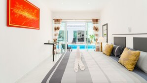 A modern hotel room with a bed, a view of a swimming pool, and a red artwork on the wall. - Wirason Villa 4 Bedrooms (Koh Samui)