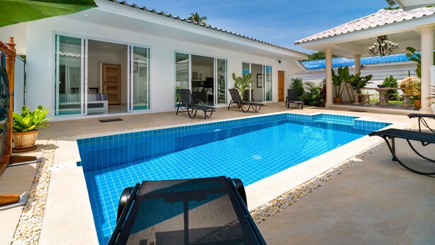 A modern pool area with a clear blue pool, sun loungers, and a covered patio with potted plants. - Wirason Villa 4 Bedrooms (Koh Samui)