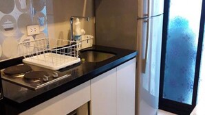 A modern kitchen with stainless steel appliances, a black countertop, and a patterned rug. - The Base Central Pattaya by Arawat (Pattaya)
