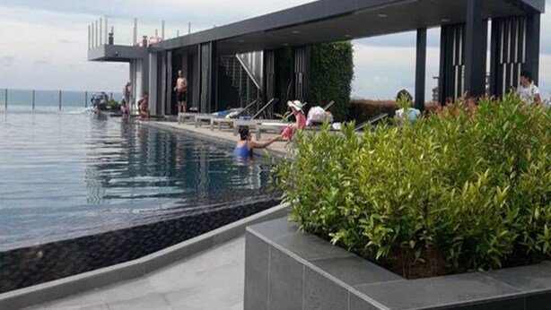 A modern outdoor pool area with a covered seating area and a view of the sea. - The Base Central Pattaya by Arawat (Pattaya)