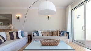 A living room with a sofa, a coffee table, a hanging light fixture, and a sliding glass door.
