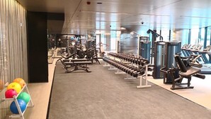 Een sportschool met diverse fitnessapparatuur, waaronder loopbanden en krachttoestellen.