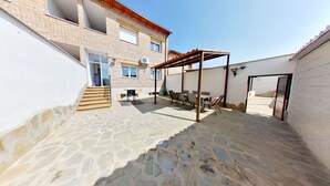 Ein Innenhof mit Steinboden, einer Holzpergola und einer Treppe, die zu einer Tür führt.
