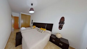 Ein Schlafzimmer mit Bett, Nachttischen, einem Kleiderschrank und einer Deckenleuchte.