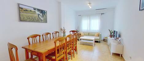Un comedor con una mesa y sillas de madera, un sofá y un armario blanco con objetos decorativos.