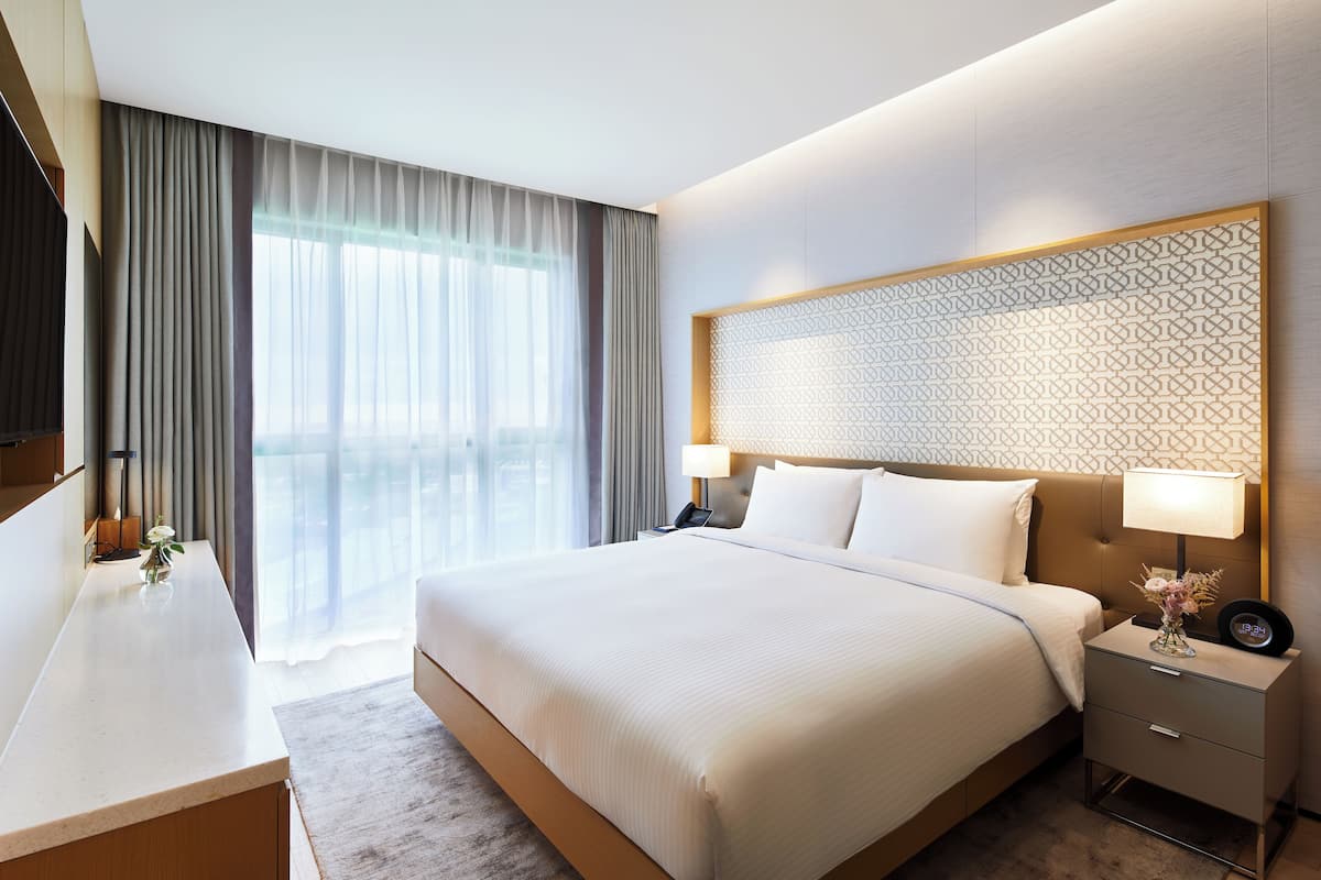Une chambre d’hôtel avec un grand lit, des tables de chevet, un bureau et une vue sur l’extérieur.