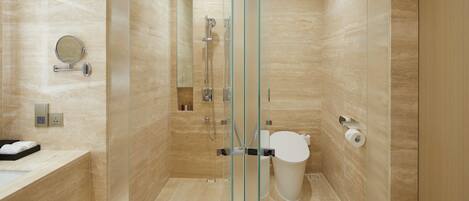 A modern bathroom with a glass shower enclosure, a toilet, and a sink with a mirror.