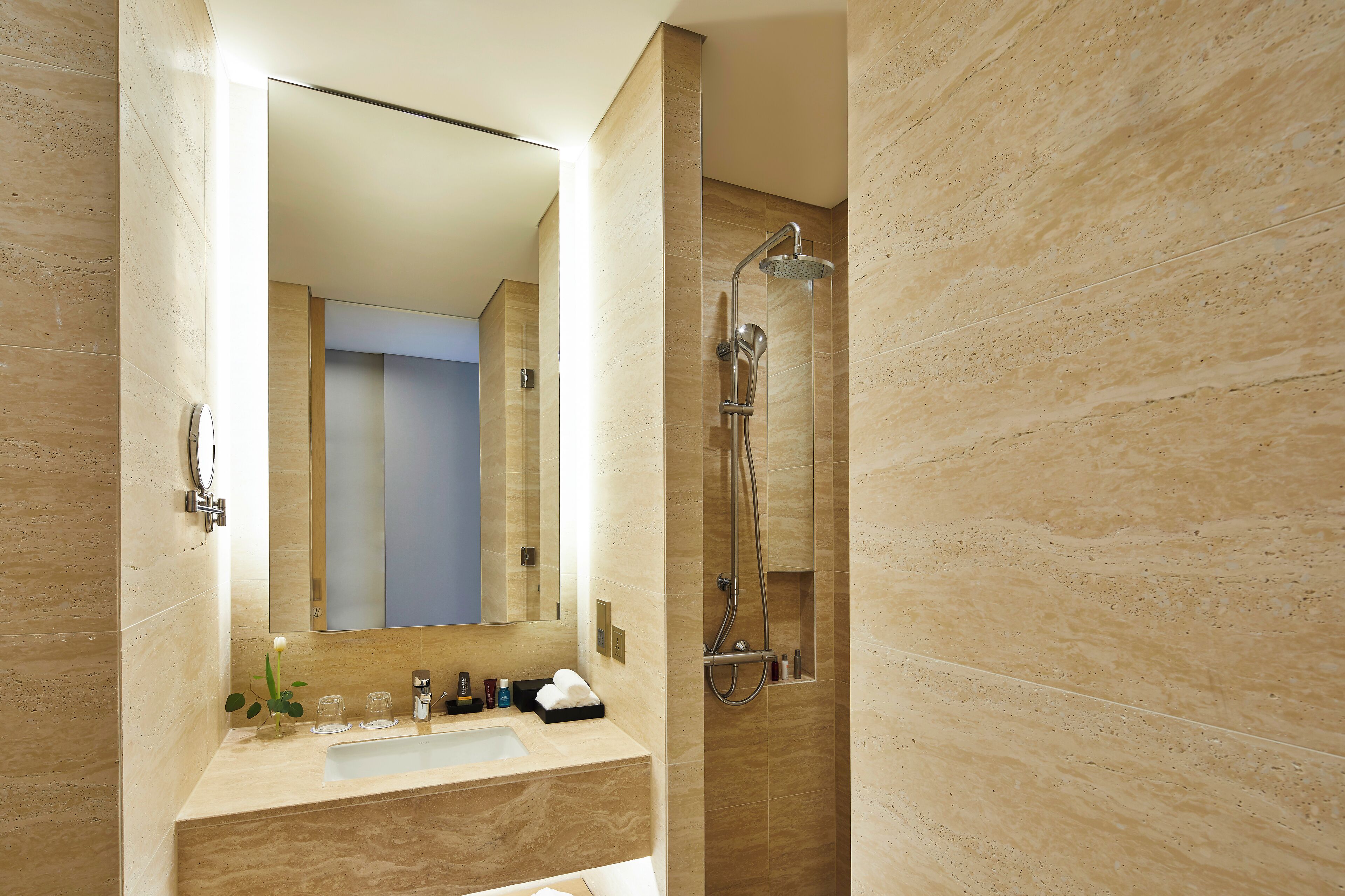 A modern bathroom with a large mirror, a sink, and a shower.