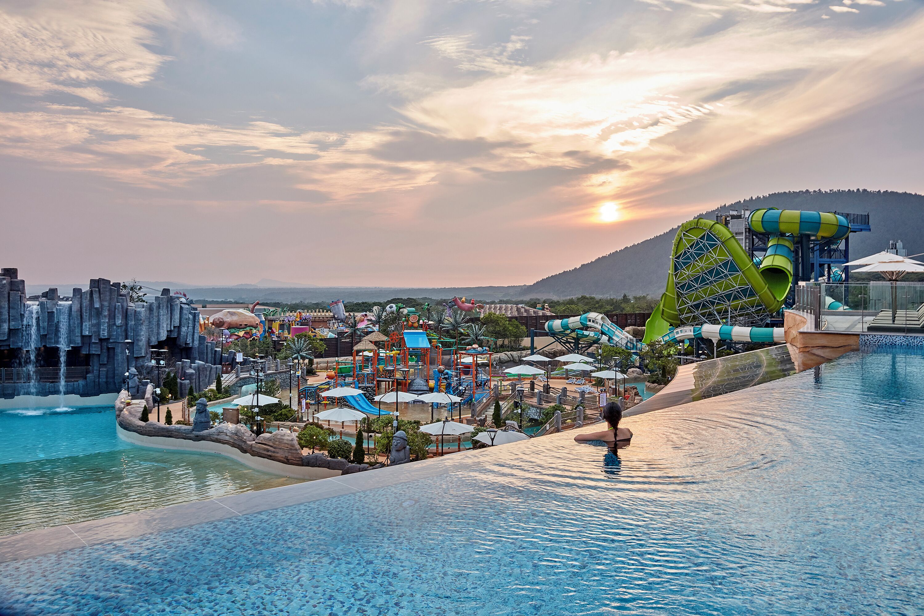 A water park with a large pool, slides, and a waterfall.