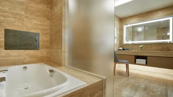 A modern bathroom with a large bathtub, a vanity with a mirror, and a chair.