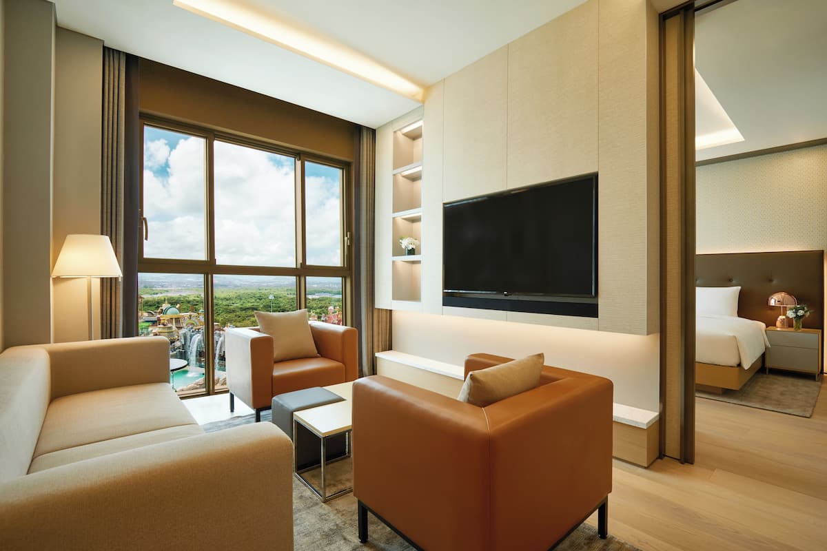 Une chambre d’hôtel moderne dotée d’une grande fenêtre, d’un téléviseur à écran plat et d’un coin salon confortable.