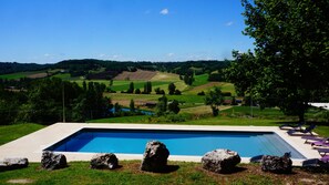 Een buitenzwembad, ligstoelen bij het zwembad