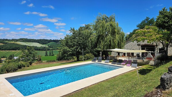 Een buitenzwembad, ligstoelen bij het zwembad