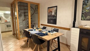 A dining area with a wooden table set for four, a spiral staircase, and a poster on the wall. - Apartment in private house with small terrace, panoramic view, external veranda (Magomadas)