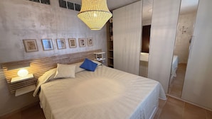 A bedroom with a bed, bedside lamps, a bedside table, a wardrobe, and a hanging light fixture. - Apartment in private house with small terrace, panoramic view, external veranda (Magomadas)