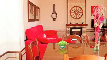 A living room with a red sofa, a wooden coffee table, and a fireplace.