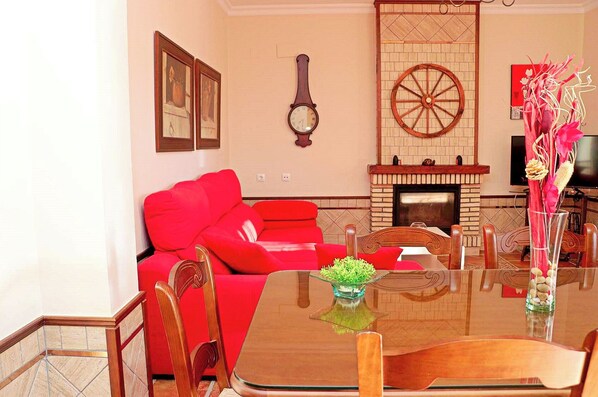 A living room with a red sofa, a wooden coffee table, and a fireplace. - Rustic holiday villa for 5 people (CONIL DE LA FRONTERA)