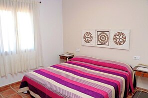 A bedroom with a bed, a nightstand, and a window with curtains. There are three wall decorations above the bed. - Rustic holiday villa for 5 people (CONIL DE LA FRONTERA)