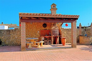 An outdoor patio with stone walls, a tiled roof, and a small brick chimney. - Rustic holiday villa for 5 people (CONIL DE LA FRONTERA)