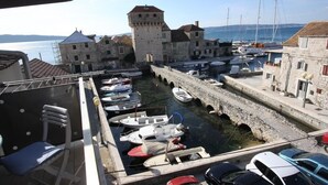 A harbor with boats docked, stone buildings, and a tower. - Modern apartment near Split and Trogir (Kaštel Gomilica)