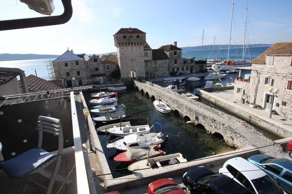 A harbor with boats docked, stone buildings, and a tower.