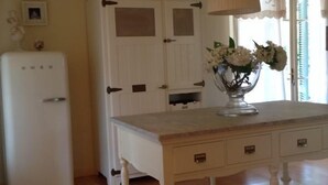 Eine Küche mit einem weißen Kühlschrank, einem weißen Schrank und einem Holztisch mit Schubladen.