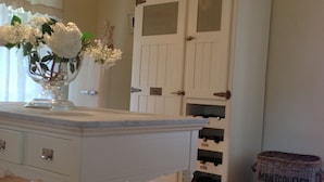 A white dresser with drawers, a vase with flowers, and a hanging lamp. - Villa Serena with Private Pool (Pietrasanta)