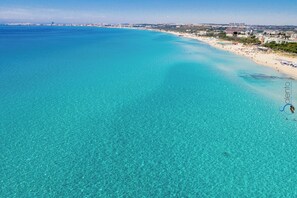 A coastal beach with clear turquoise waters and a sandy shore.