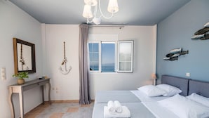 Een slaapkamer met een bed, een bureau, een stoel, een raam met uitzicht en een hangende anker.