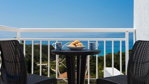 Een balkon met een tafel gedekt voor twee personen, inclusief een schaal gebak en twee versierde kopjes.