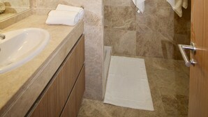 Ein modernes Badezimmer mit Marmorboden, Waschbecken, Spiegel und zwei Handtüchern, die an der Wand hängen.
