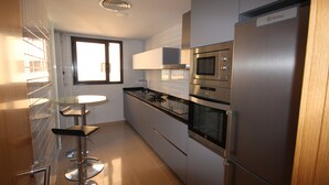 Eine moderne Küche mit Edelstahlgeräten, einem Bartisch mit Glasplatte und einem Fenster für natürliches Licht.