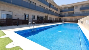 A modern building with a swimming pool, multiple balconies, and a brick facade.