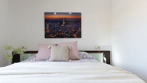 A neatly made bed with a white duvet, two pillows, and a nightstand with a lamp.