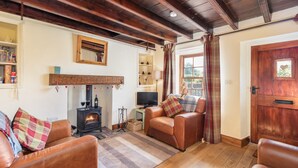 A cozy living room with leather sofas, a fireplace, a television, and a wooden door with a heart decoration. - The Cottage Gillamoor York, with wood burner, wifi and good local pub (Gillamoor)