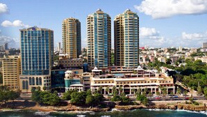 Paisagem costeira com três edifícios altos imponentes, um hotel à beira-mar com vários andares, e uma combinação de edifícios residenciais e comerciais.
