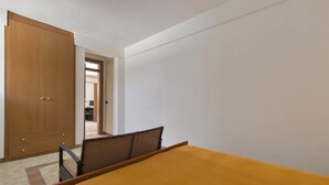 A bedroom with a bed, a wooden wardrobe, and a chair. - Girasole Trilo 2 by BarbarHouse (Castrignano del Capo)
