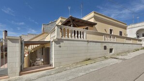 A two-story house with a balcony, a gated entrance, and a small patio area. - Girasole Trilo 2 by BarbarHouse (Castrignano del Capo)