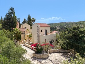 A hillside property with stone buildings, a stone pathway, and lush greenery.