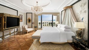 Un dormitorio lujoso con una cama grande, televisión, candelabro y vistas al mar.