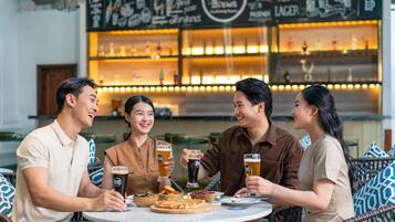 A group of people sitting at a round table in a restaurant with a bar in the background.