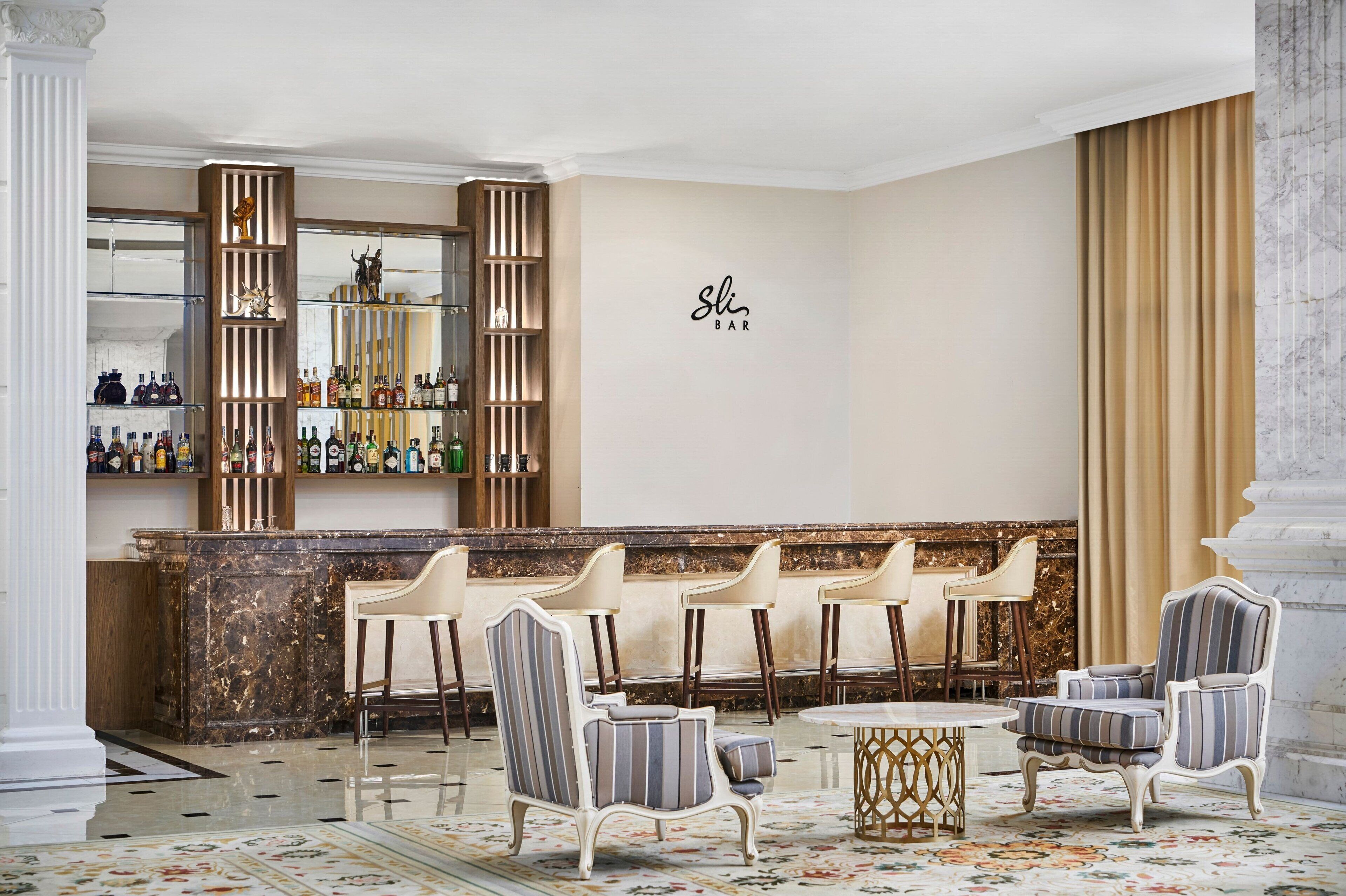 A bar area with a marble countertop, striped chairs, and a decorative mirror.