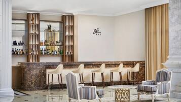 A bar area with a marble countertop, striped chairs, and a decorative mirror.