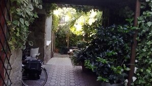 A narrow pathway leading to a covered area with a bicycle parked on the left.